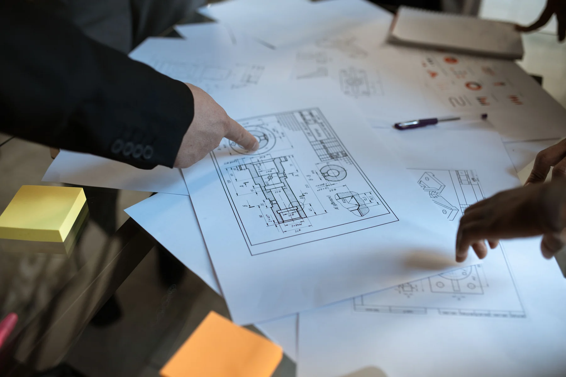 Des mains échangent autour de plans techniques